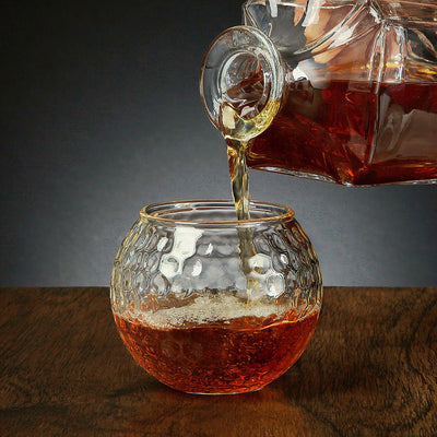 Decanter pouring whiskey on a Golf Ball Whiskey Glass