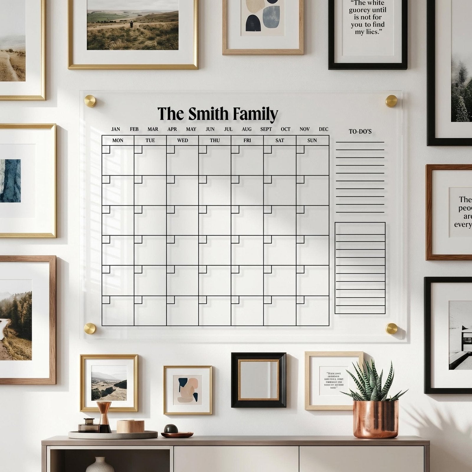 Acrylic family wall calendar with gold standoffs displayed on a gallery wall