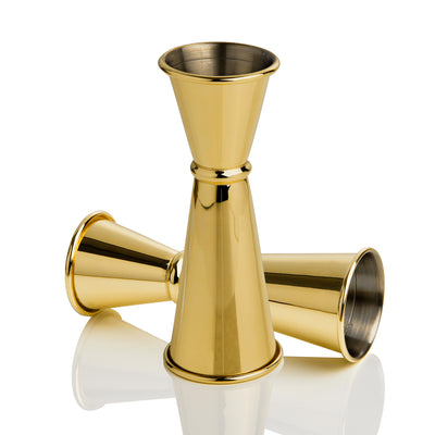 Three gold metal jiggers, one upright and two lying on their sides on a white background.
