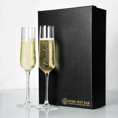 two customized champagne glasses sitting on a table next to a black luxury box