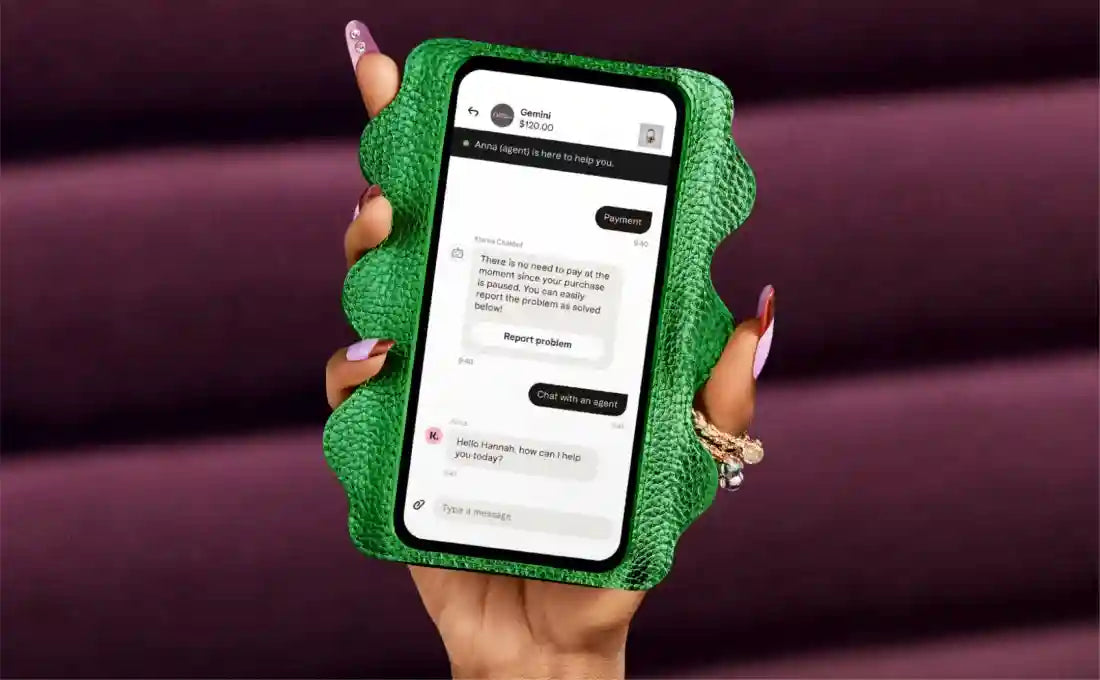 Hand holding smartphone in a green textured case showing a support chat with buttons “Payments” and “Report problem”.