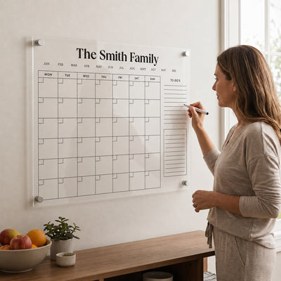 Woman writing on a personalized acrylic wall calendar labeled “The Smith Family"