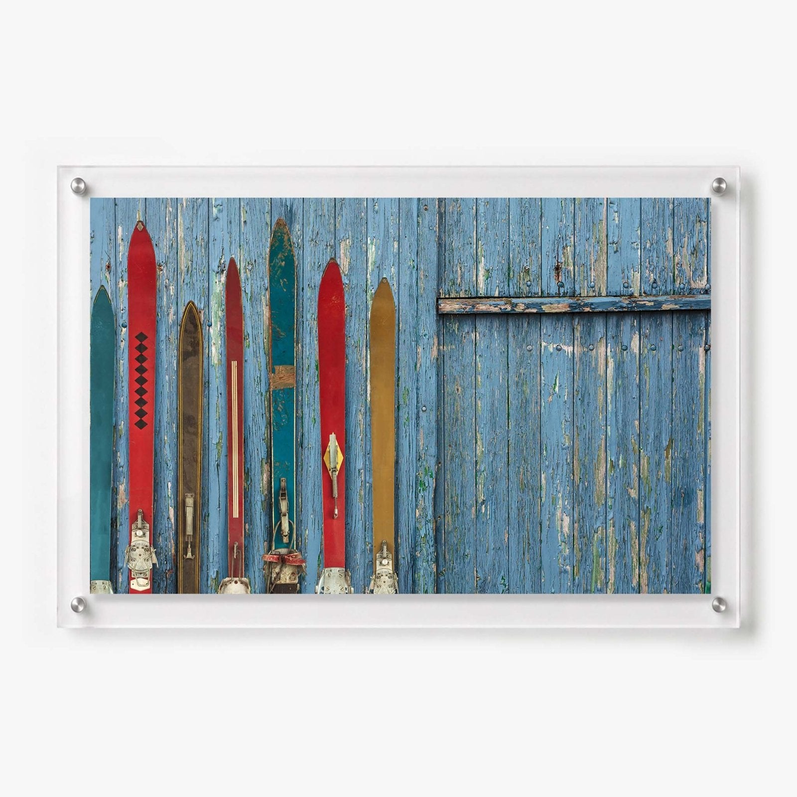 Vintage alpine skis displayed against a weathered blue wooden wall